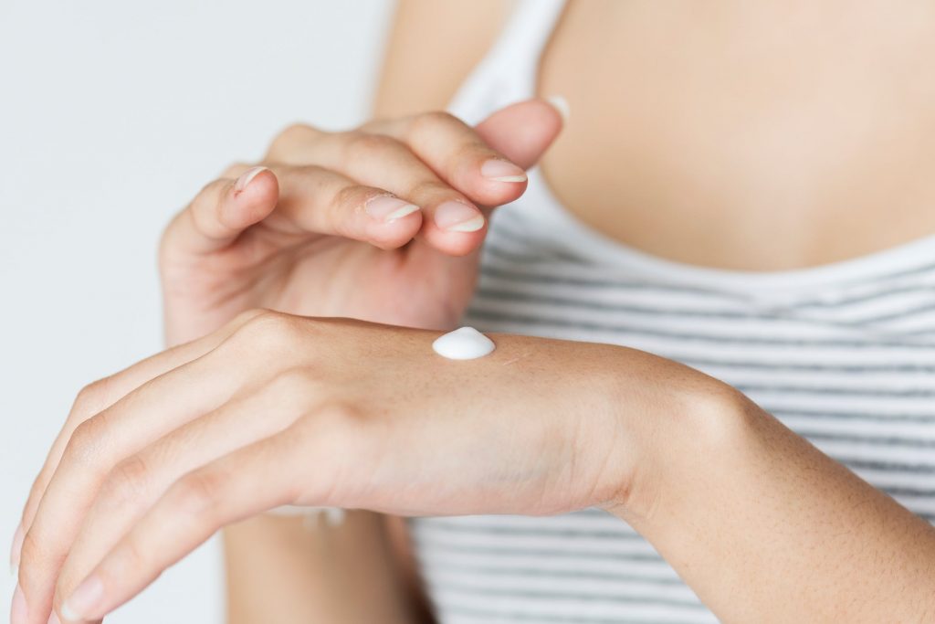 woman applying moisturizer on her hand